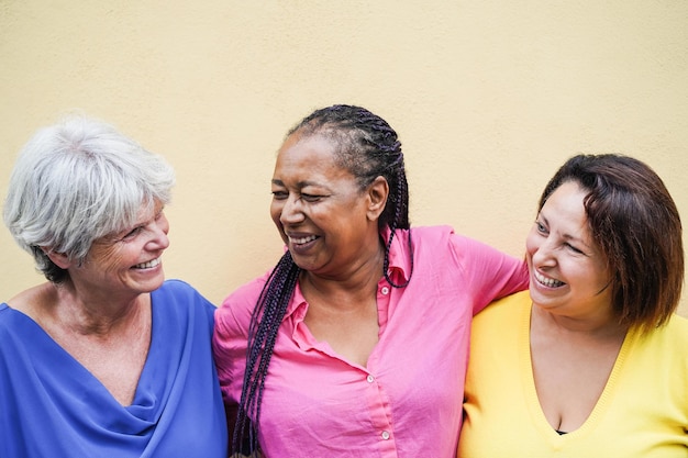 Mujeres mayores multirraciales que se divierten abrazándose juntas al aire libre - Centrarse en el rostro femenino africano