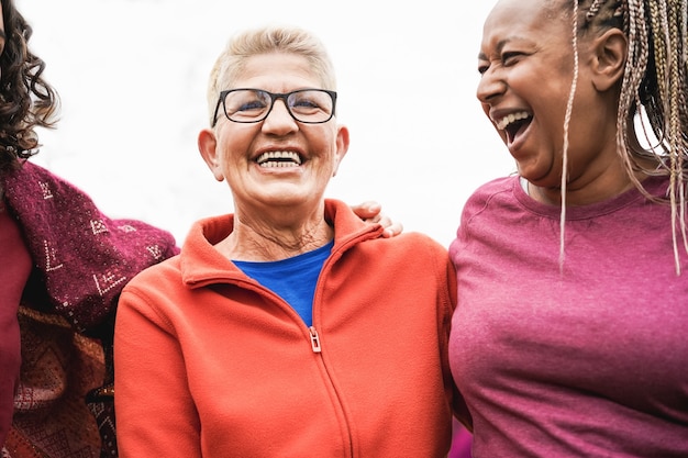 Mujeres mayores multirraciales que se divierten juntas después del entrenamiento deportivo al aire libre - Centrarse en el rostro de la mujer del centro