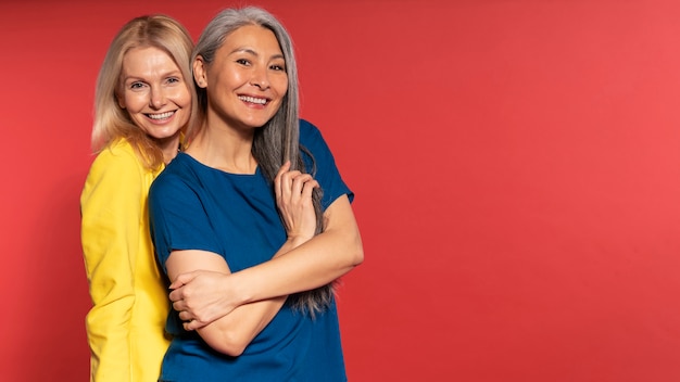 Foto mujeres mayores posando y sonriendo contra un fondo rojo