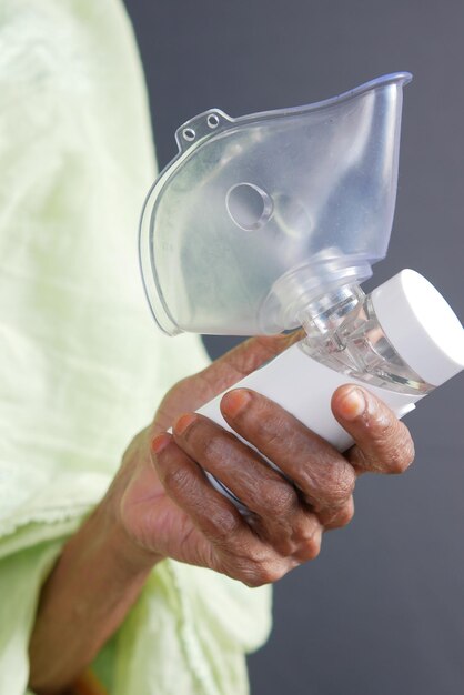 Las mujeres mayores sostienen un nebulizador contra un fondo gris claro