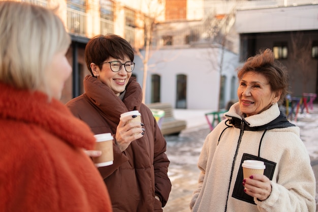 Mujeres mayores tomando café al aire libre y hablando