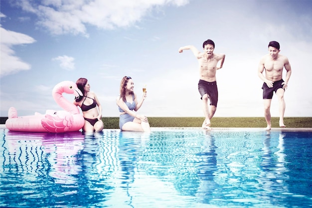 Mujeres mirando amigos saltando a la piscina