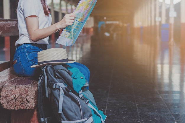 Mujeres, mochila azul y sombrero en la estación de tren con turistas. Ideas de viaje