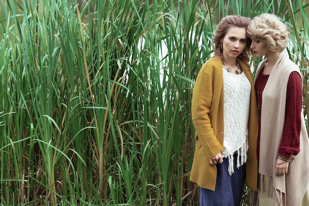 Mujeres de moda posando juntos al aire libre, parque de otoño