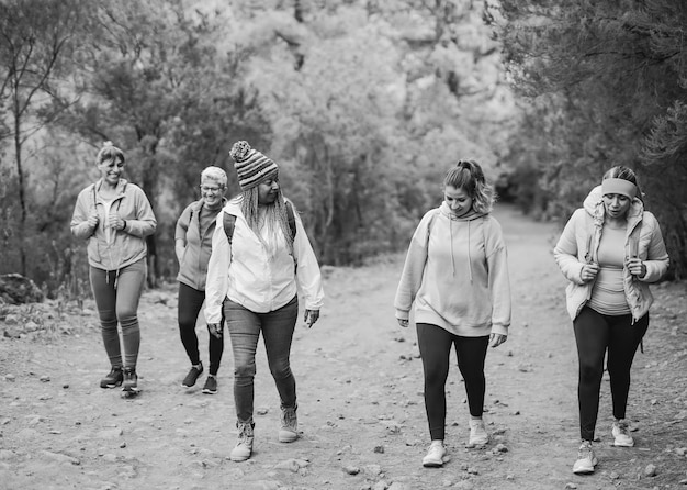 Mujeres multiétnicas divirtiéndose durante el día de caminata en el bosque de montaña Edición en blanco y negro