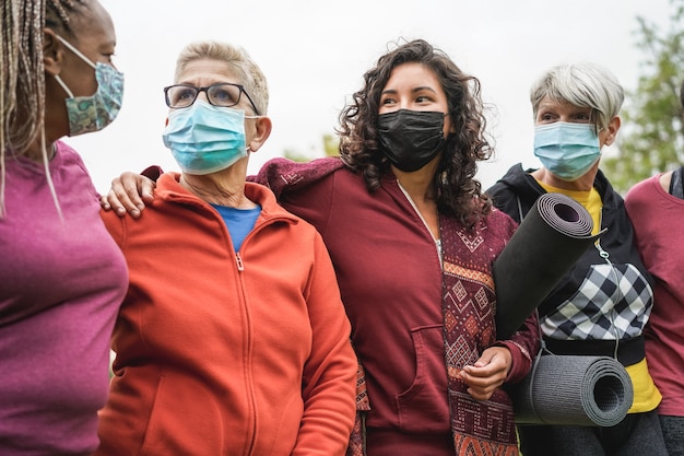 Mujeres multigeneracionales que se divierten juntas después del entrenamiento deportivo al aire libre durante el brote de coronavirus: enfoque principal en la cara de niña del centro