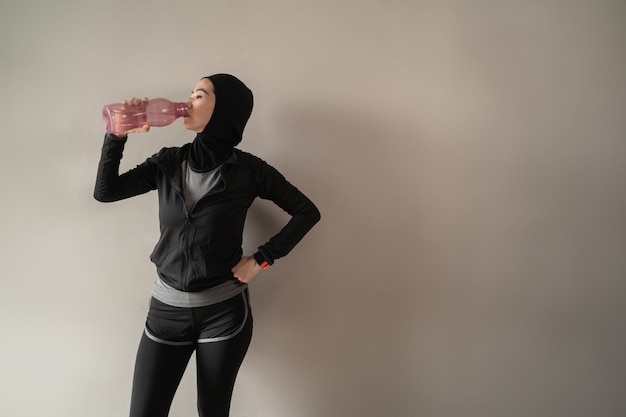 Mujeres musulmanas asiáticas que usan ropa deportiva hijab cuando beben botellas de agua