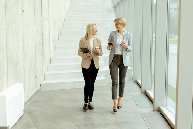 Mujeres de negocios caminando en el pasillo de la oficina