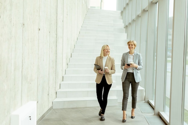 Mujeres de negocios caminando en el pasillo de la oficina