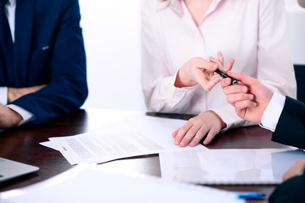 Mujeres de negocios dando un bolígrafo al hombre de negocios para firmar un contrato