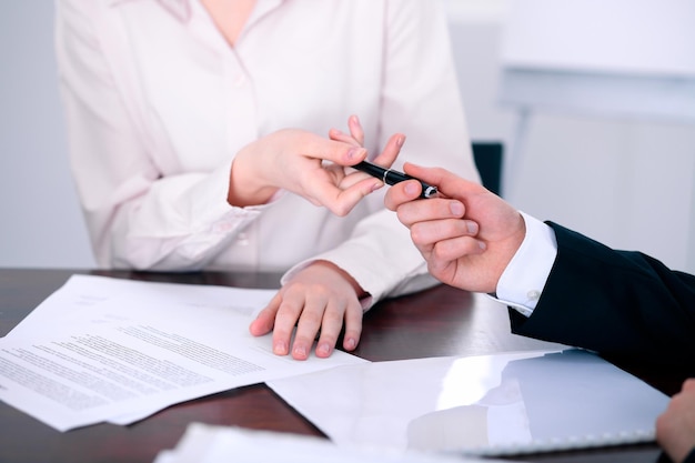 Mujeres de negocios dando un bolígrafo a un hombre de negocios para firmar un contrato.