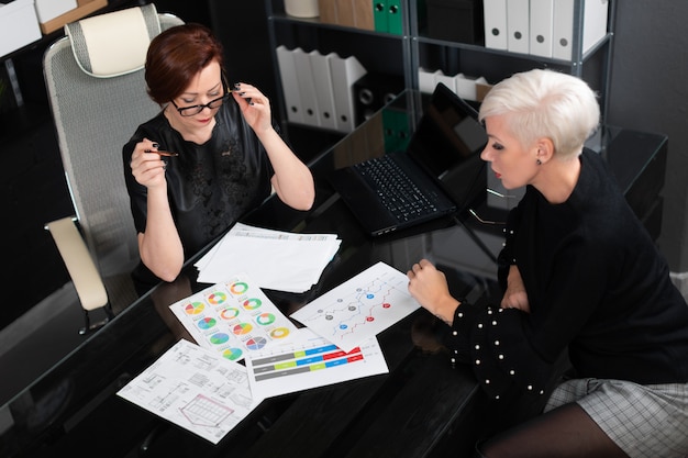 Las mujeres de negocios discuten diagramas en el escritorio en la oficina