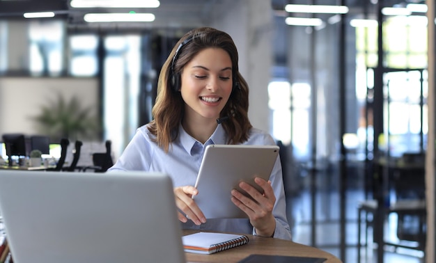 Mujeres de negocios independientes que usan una videoconferencia de llamada de trabajo de tableta con el cliente en el lugar de trabajo en la oficina moderna