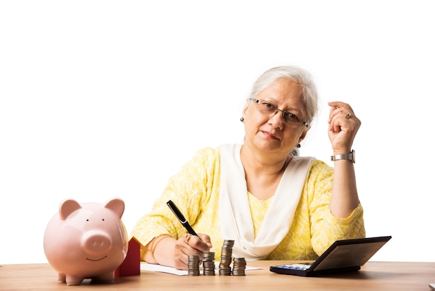 Mujeres de negocios indias o asiáticas mayores que ahorran o mantienen o calculan monedas monetarias. Concepto de negocio, finanzas e inversión