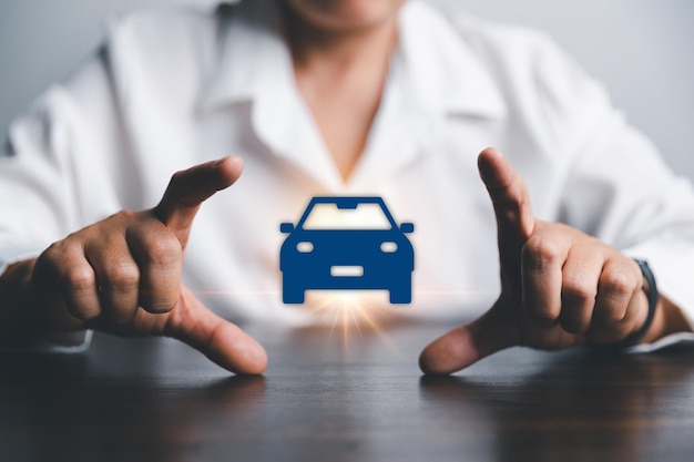 Mujeres de negocios mano protegiendo icono azul coche en el escritorio Planificación para administrar los costos de financiación de transporte Concepto de seguro de coche negocio ahorro compra venta con impuestos y préstamo para coche nuevo