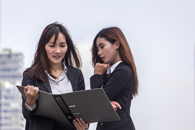 Las mujeres de negocios miran y sonríen conversación con archivo de informe