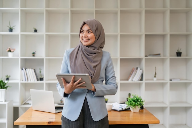 Mujeres de negocios musulmanas felices con hijab en el trabajo mujer árabe sonriente sosteniendo una tableta