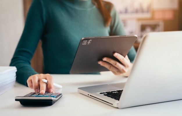 Mujeres de negocios o contadoras que trabajan en computadoras portátiles con documentos comerciales y calculadoras en la mesa de oficina en la oficina