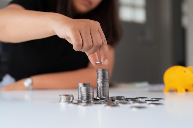 Las mujeres de negocios ponen una pila de monedas y muchos billetes en la oficina para ahorrar dinero para el futuro y la jubilación.