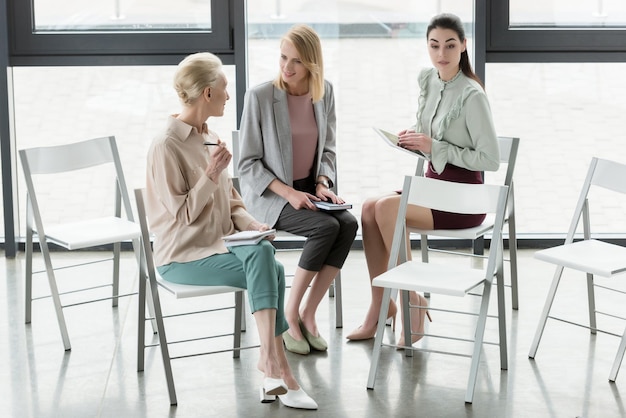 mujeres de negocios profesionales sentadas en sillas y hablando en la oficina