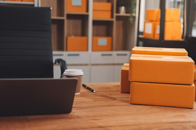 Las mujeres de negocios de las PYME asiáticas usan computadoras portátiles para comprobar los pedidos de los clientes, cajas de envío en línea en casa, comenzando un pequeño empresario, PYME freelance, negocios en línea, trabajo en casa.