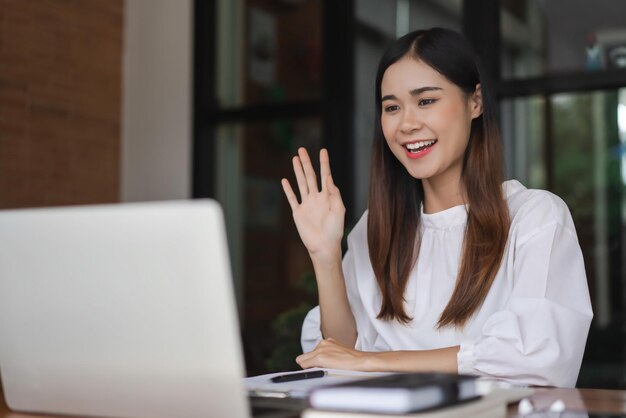 Foto mujeres de negocios se reúnen y saludan con un colega en una llamada de video mientras trabajan fuera de la oficina