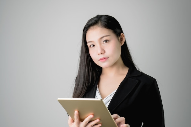 Las mujeres de negocios sonrientes están sosteniendo la tableta y están utilizando aplicaciones en línea.