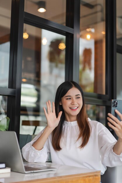 Las mujeres de negocios usan el teléfono inteligente para saludar a sus colegas en videoconferencias y trabajar fuera de la oficina