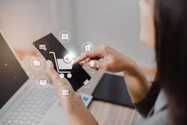 Mujeres de negocios usan teléfonos móviles tocando con carros de compras virtuales e iconos de comercio electrónico como el carrito de crédito, el camión de entrega, el porcentaje de ventas para el concepto de compras en línea