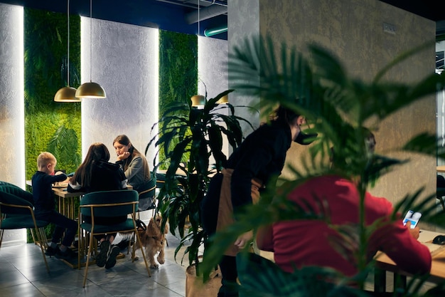 Las mujeres con un niño pequeño y un perro cenan en un restaurante.