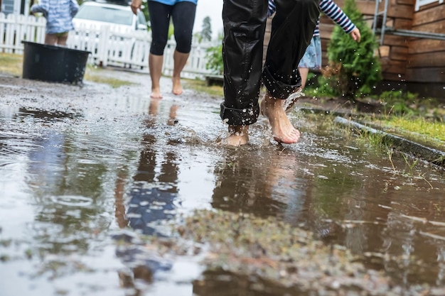 Las mujeres con niños corren alegremente descalzos por los charcos después de la lluvia