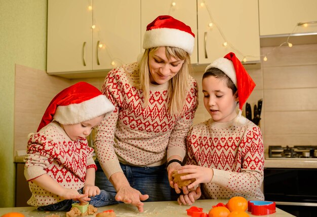 Mujeres y niños pequeños horneando postres caseros de pasteles navideños