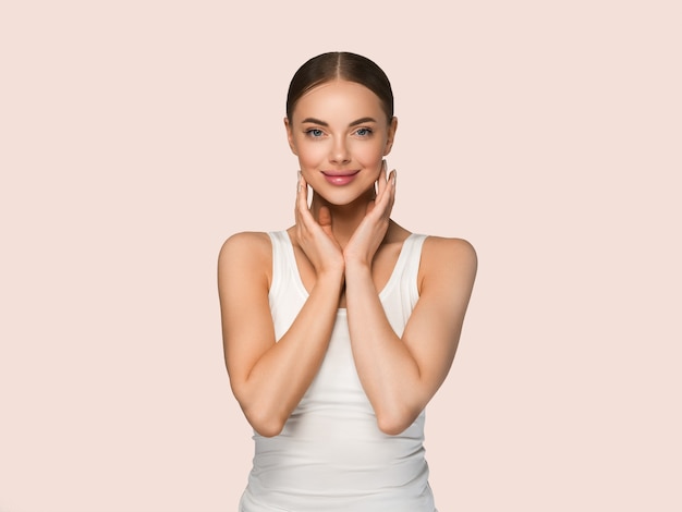 Mujeres de la piel sana de la belleza que tocan el retrato cosmético del estudio de la cara. Ropa deportiva color fondo amarillo