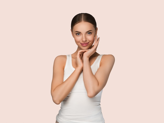 Mujeres de la piel sana de la belleza que tocan el retrato cosmético del estudio de la cara. Ropa deportiva color fondo amarillo