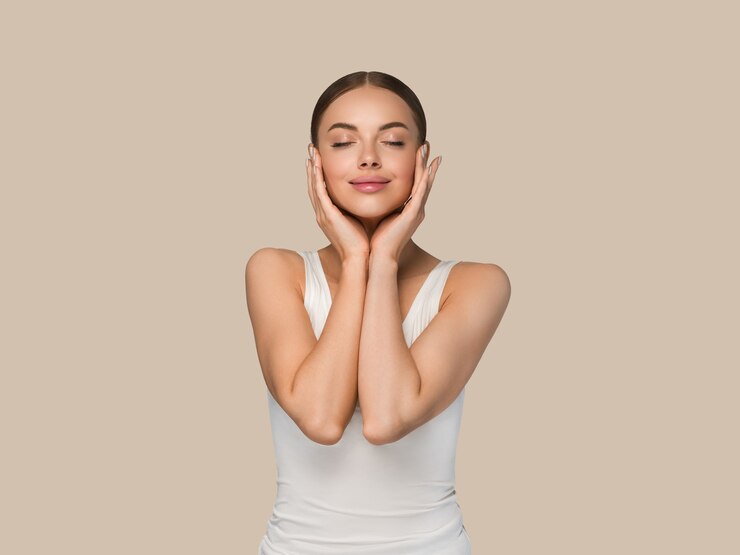 Foto mujeres de la piel sana de la belleza que tocan el retrato cosmético del estudio de la cara. ropa deportiva color fondo marrón