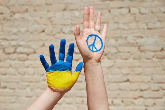 Las mujeres pintadas a mano con los colores de la bandera ucraniana y el signo de la paz contra la pared detienen la guerra