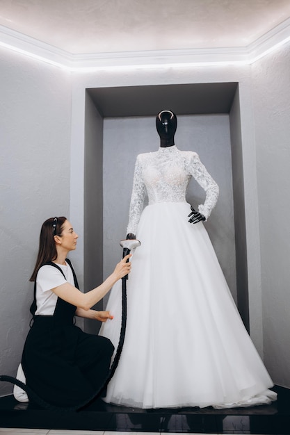 Mujeres planchando vestido de novia en estudio por máquina de planchar Concepto de boda