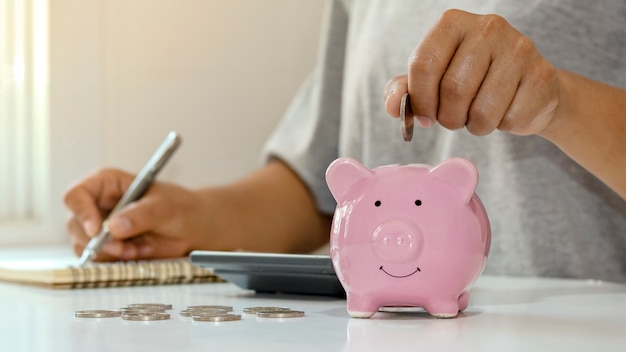 Las mujeres ponen monedas de plata en los lechones para ahorrar dinero y ahorrar dinero para futuras inversiones. Concepto financiero.