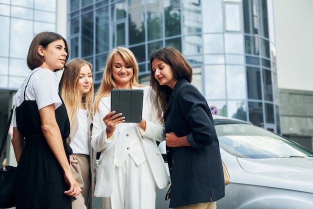 Las mujeres positivas en ropa formal están juntas al aire libre en la ciudad