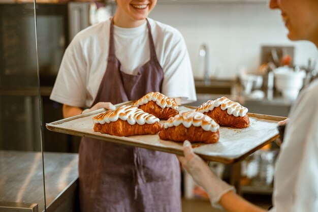 Las mujeres positivas sostienen deliciosos croissants decorados en panadería artesanal closeup