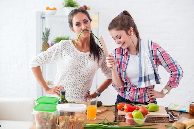 Foto mujeres preparando comida saludable jugando con verduras en la cocina divirtiéndose concepto dieta nutrición