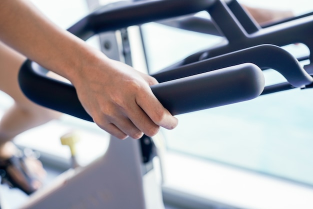 Mujeres del primer que se resuelven en gimnasio en la bicicleta estática