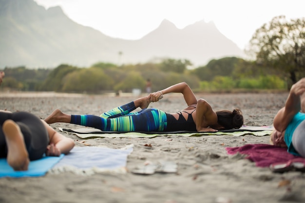 Las mujeres que hacen ejercicios de yoga o paloma apoyada posan en la montaña en la playa vacía del océano Índico en Mauricio