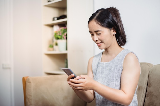 Mujeres que operan teléfonos móviles en sofás, teléfonos inteligentes