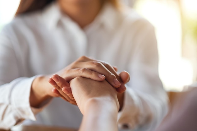 Mujeres que se toman de la mano por consuelo y simpatía.