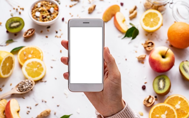 Mujeres que se toman de la mano usando un teléfono inteligente en un fondo de comida saludable