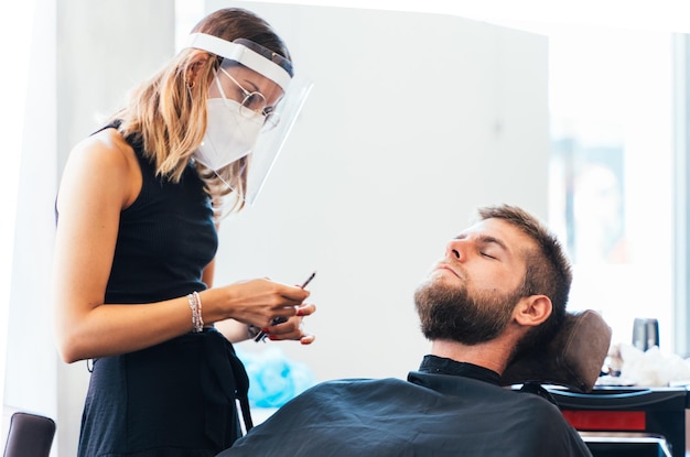 Mujeres que trabajan en una peluquería afeitando a un hombre