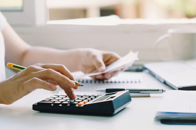 Mujeres que usan la calculadora para calcular las facturas domésticas en el hogar.