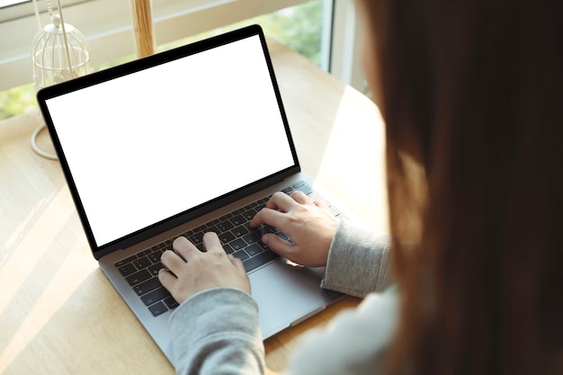 Mujeres que usan la computadora portátil con pantalla en blanco en la mesa en la oficina