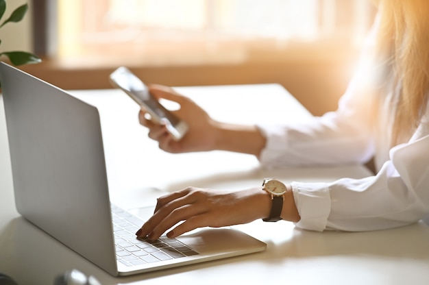 Mujeres que usan la computadora portátil y el teléfono inteligente en el escritorio de oficina.